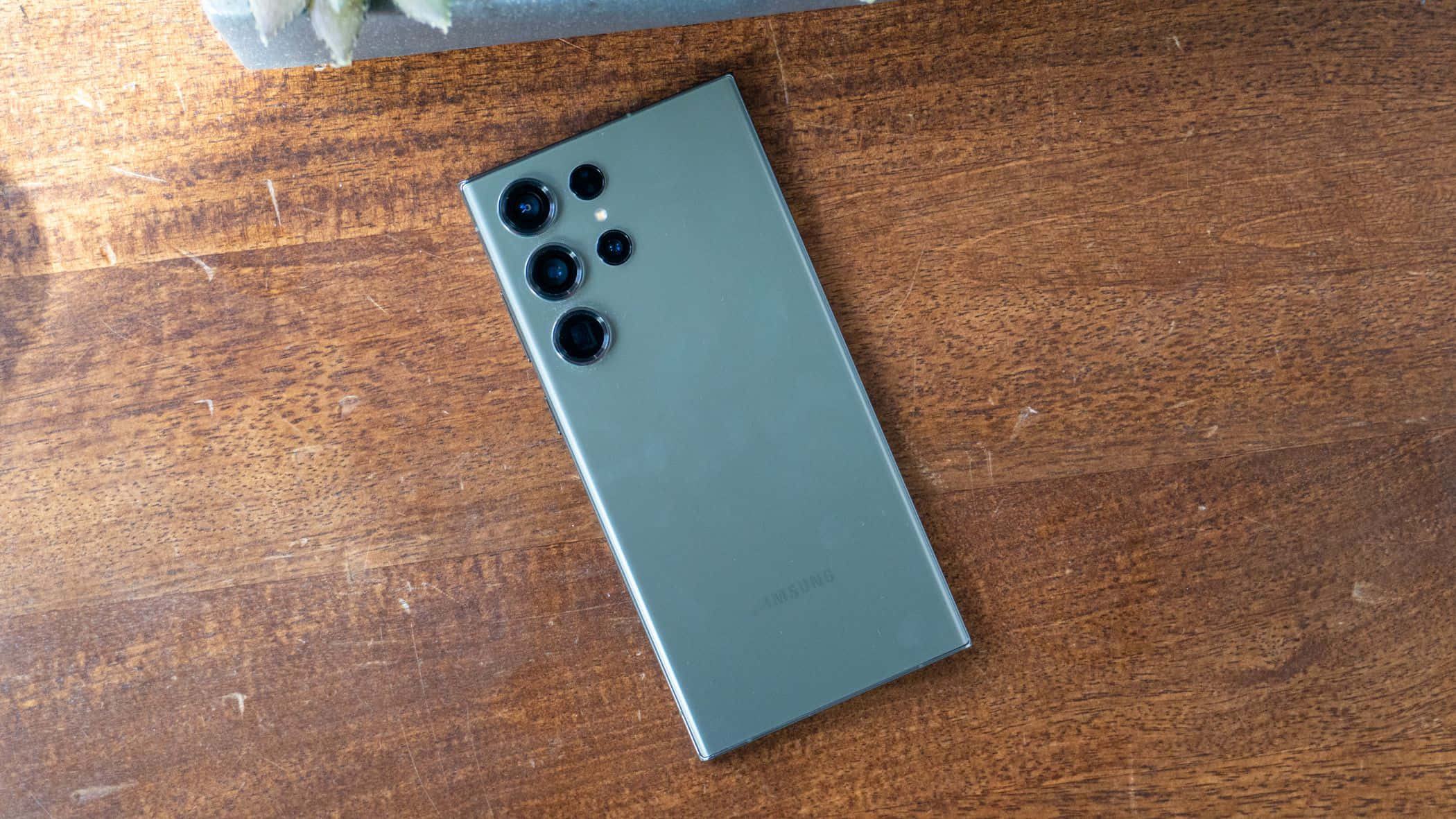 Samsung S23 Ultra зеленая задняя панель массив камер деревянная поверхность Обои