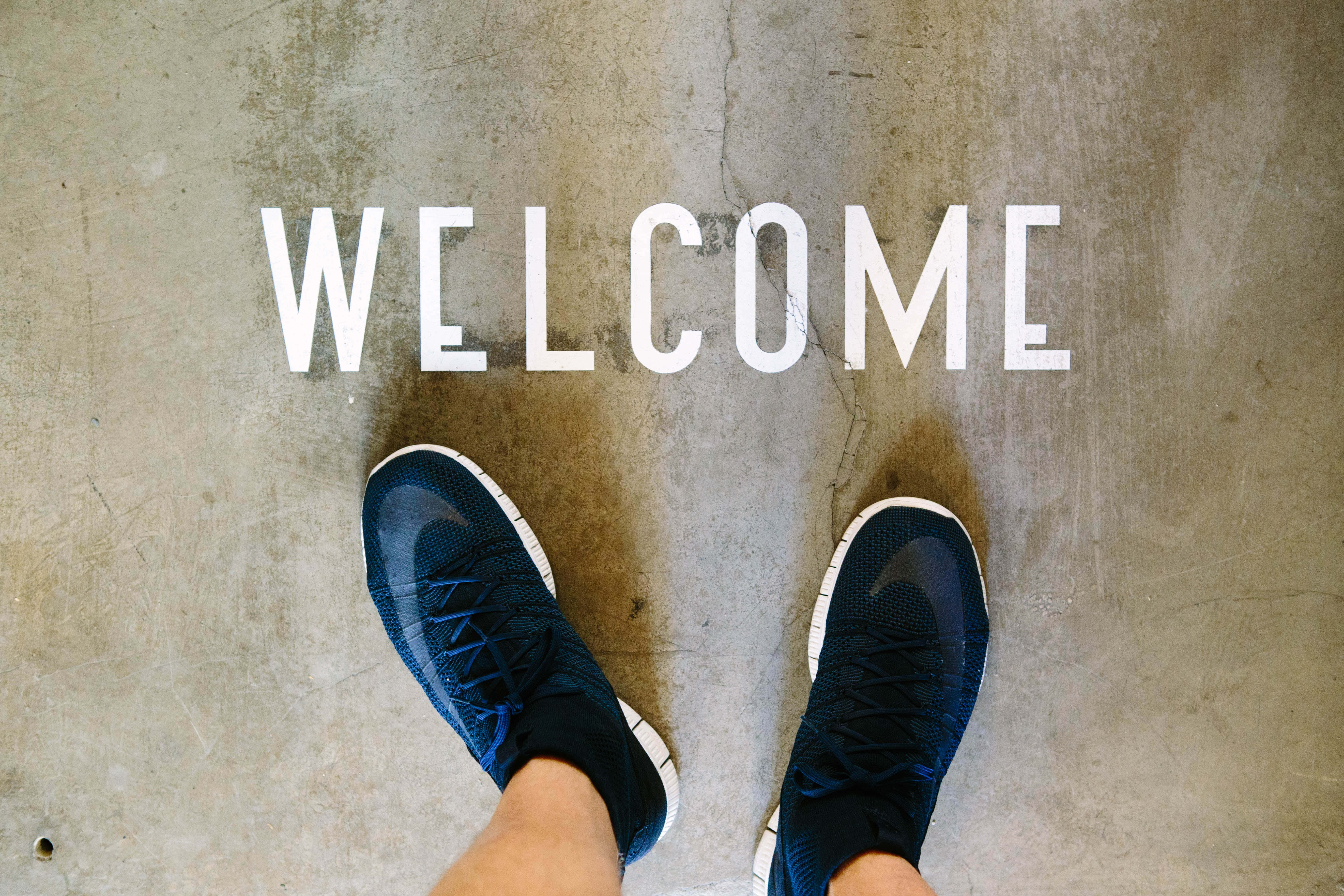 ноги человека, стоящего на бетонном полу, со словом welcome Обои