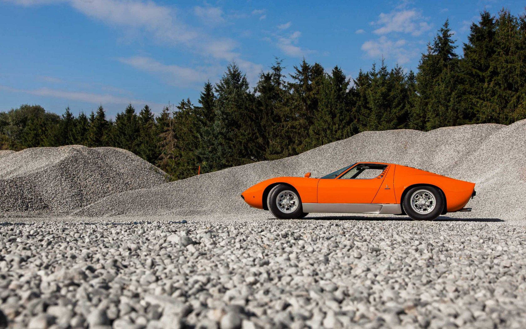 Обои с оранжевым Lamborghini Miura на гравии.