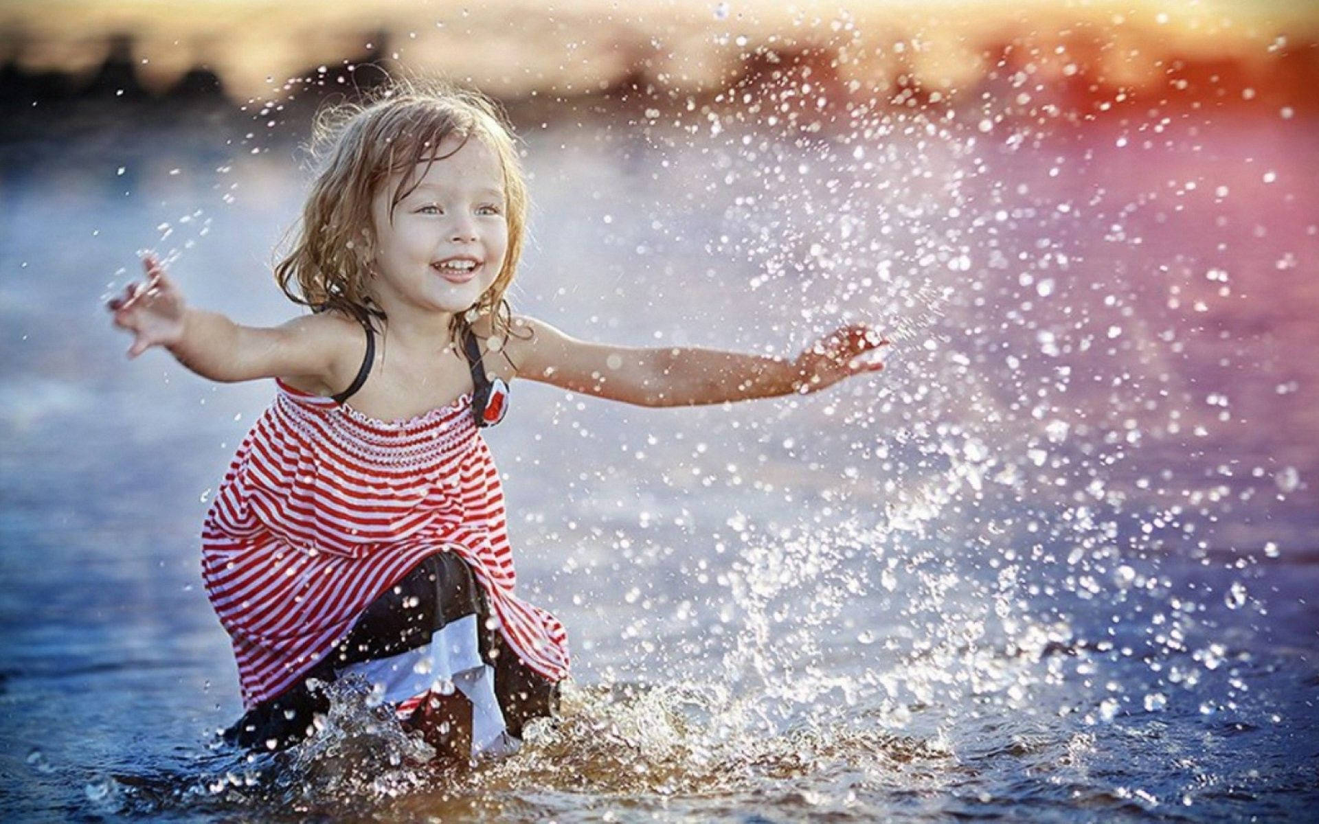 Маленькая девочка играет с водой Обои