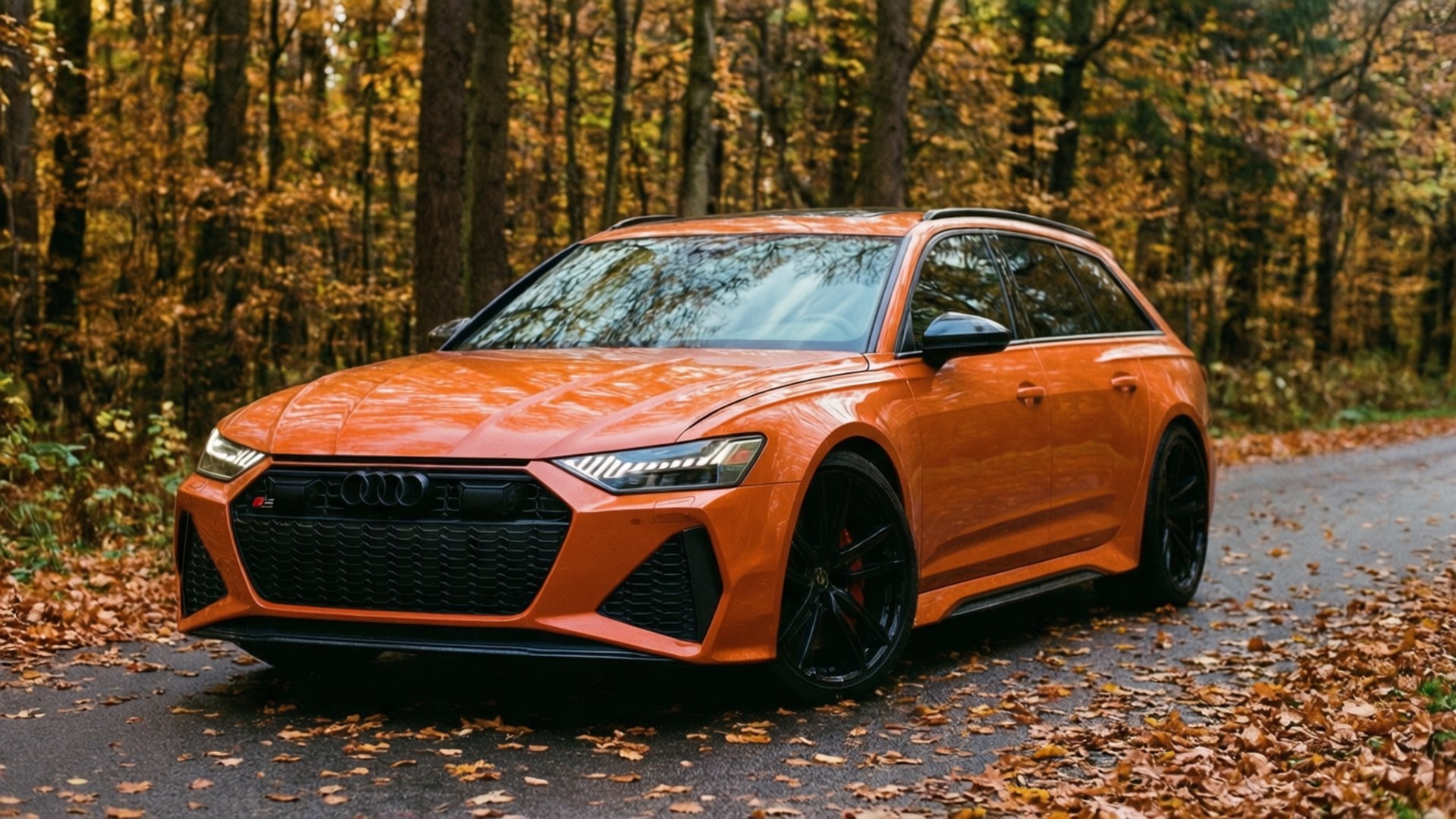 Оранжевый Audi RS6 Avant на осенней лесной дороге с падающими листьями.