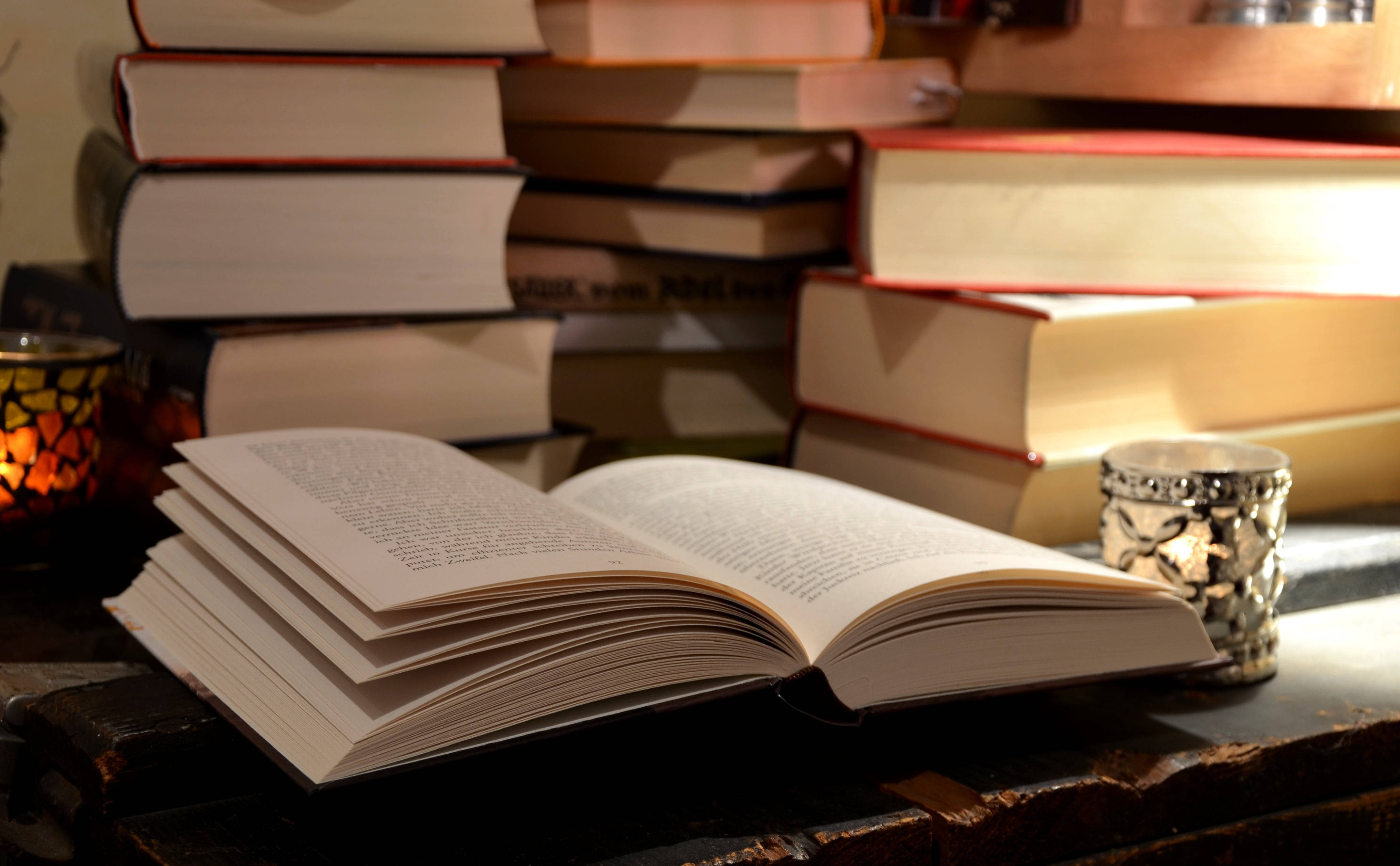 Открытая книга на столе в окружении других справочников Обои