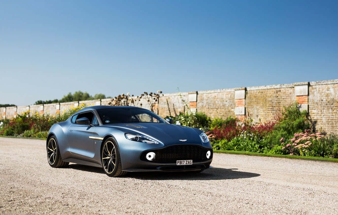 Потрясающий Aston Martin Vanquish в движении на живописной дороге Обои