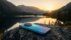 Телефон Huawei на камне с видом на горное озеро на закате, безмятежный пейзаж.