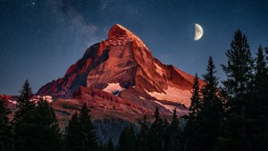 Величественная красная горная вершина, освещенная лунным светом под звездным ночным небом.