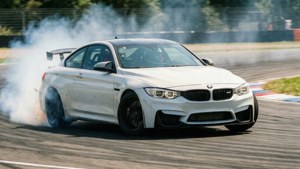 Белый BMW M4 дрифтует на повороте гоночной трассы с дымом от шин и размытием движения. — Bmw Обои