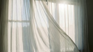 Белые тюлевые шторы, развевающиеся на солнце, успокаивающие, неземные обои.