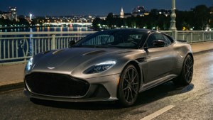 Обои Aston Martin DBS Superleggera на мосту ночью в свете городских огней.