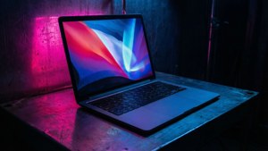 Киберпанк-вдохновленный MacBook с неоновыми отражениями в темной комнате.