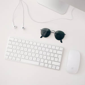 Минималистичные обои белой установки Apple MAC, состоящей из iMAC, беспроводной клавиатуры, магической мыши и наушников.