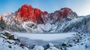 Зимний пейзаж с красной горой, покрытой снегом, и замерзшим озером