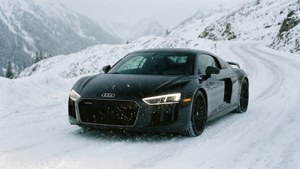 Обои Черный Audi R8 едет по заснеженной альпийской дороге под падающим снегом.